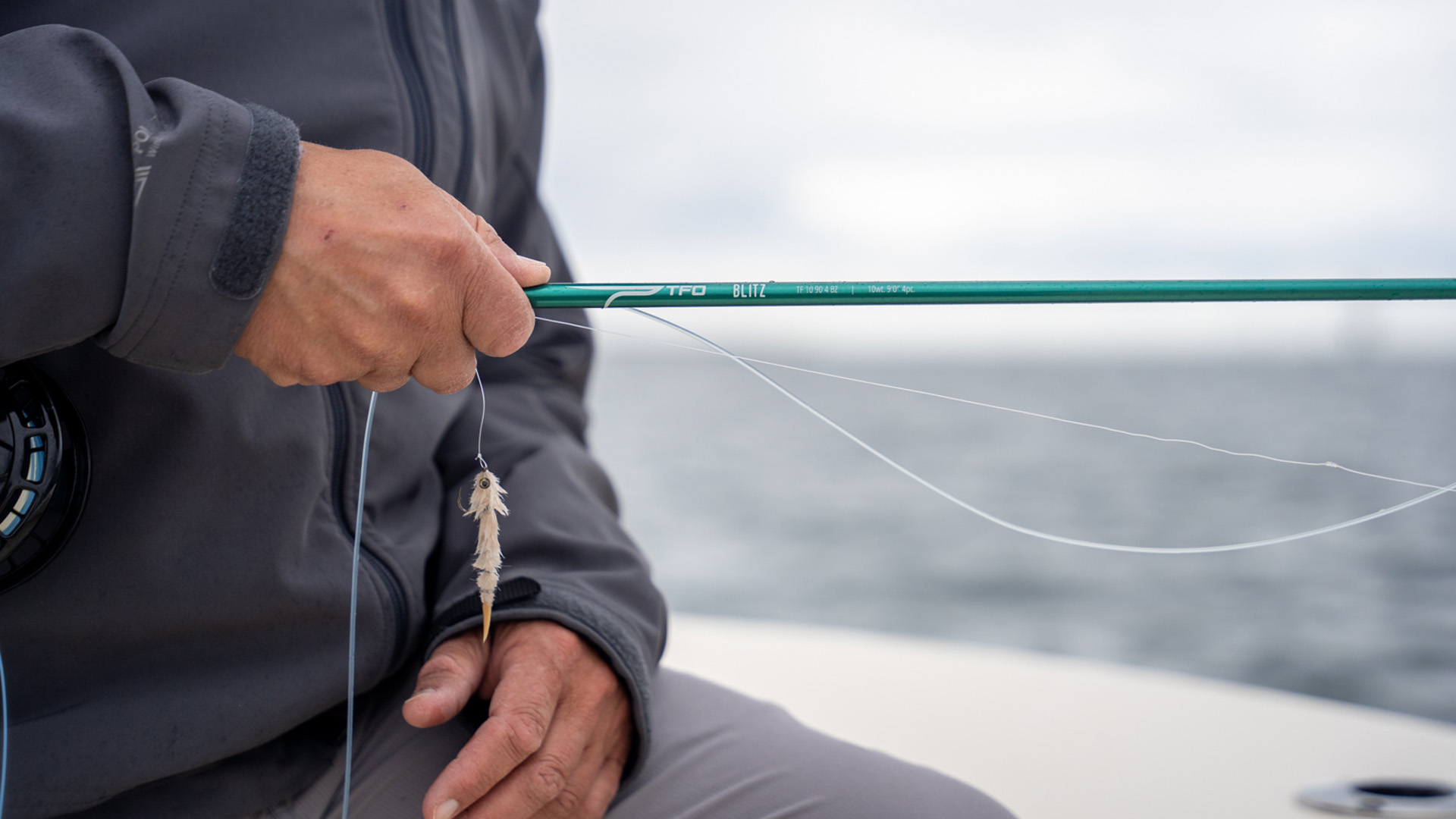 Angler holds a TFO Blitz fly rod rigged with a baitfish imitation fly, ready for false albacore.