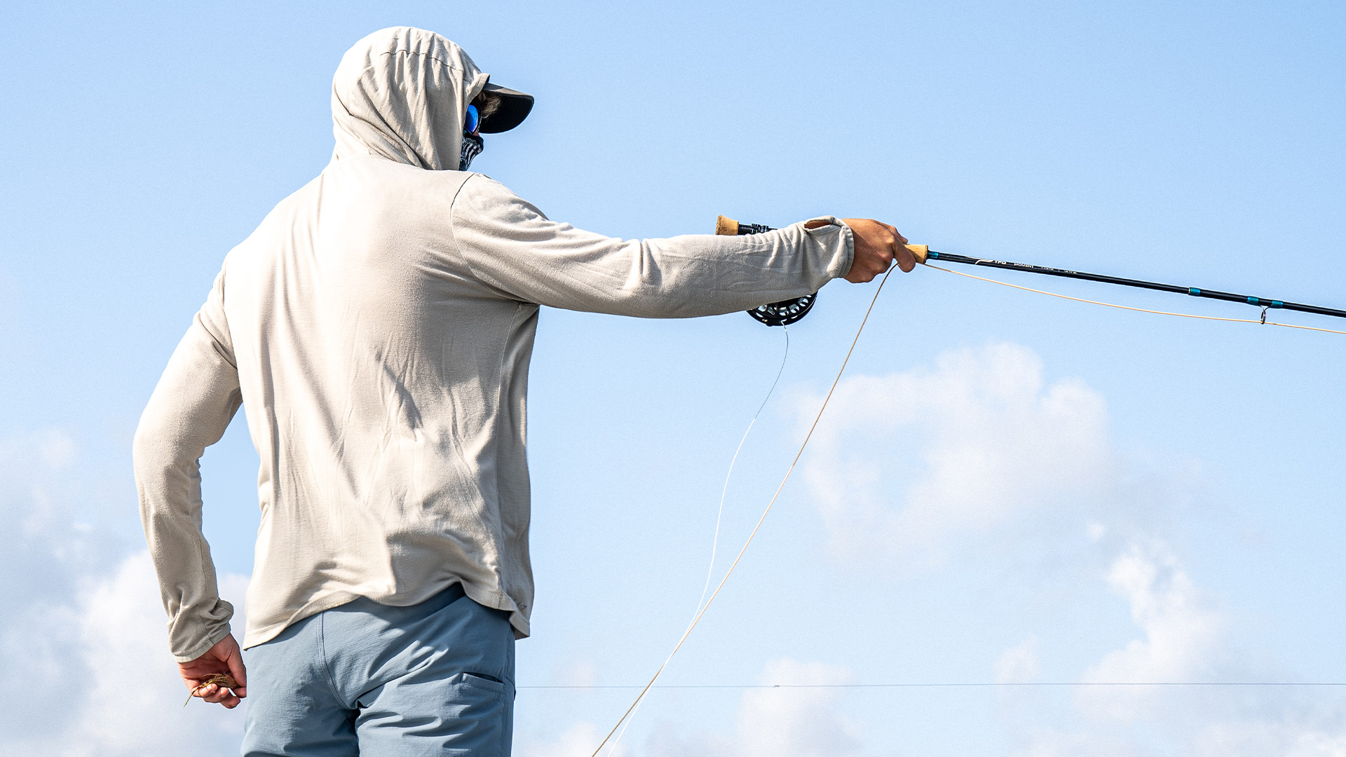Angler makes a sight cast with a TFO Moment fly rod on a clear day, line extended and fly in hand.
