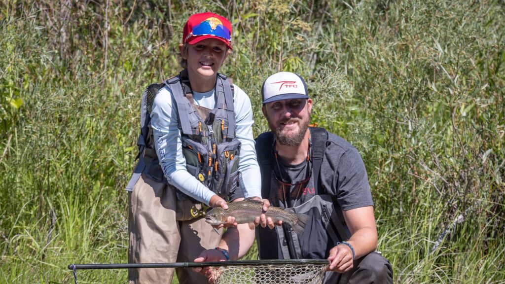 Nick Conklin and a young angler holding a rainbow trout during the TFO fly fishing school on the South Platte River in Lake George, Colorado