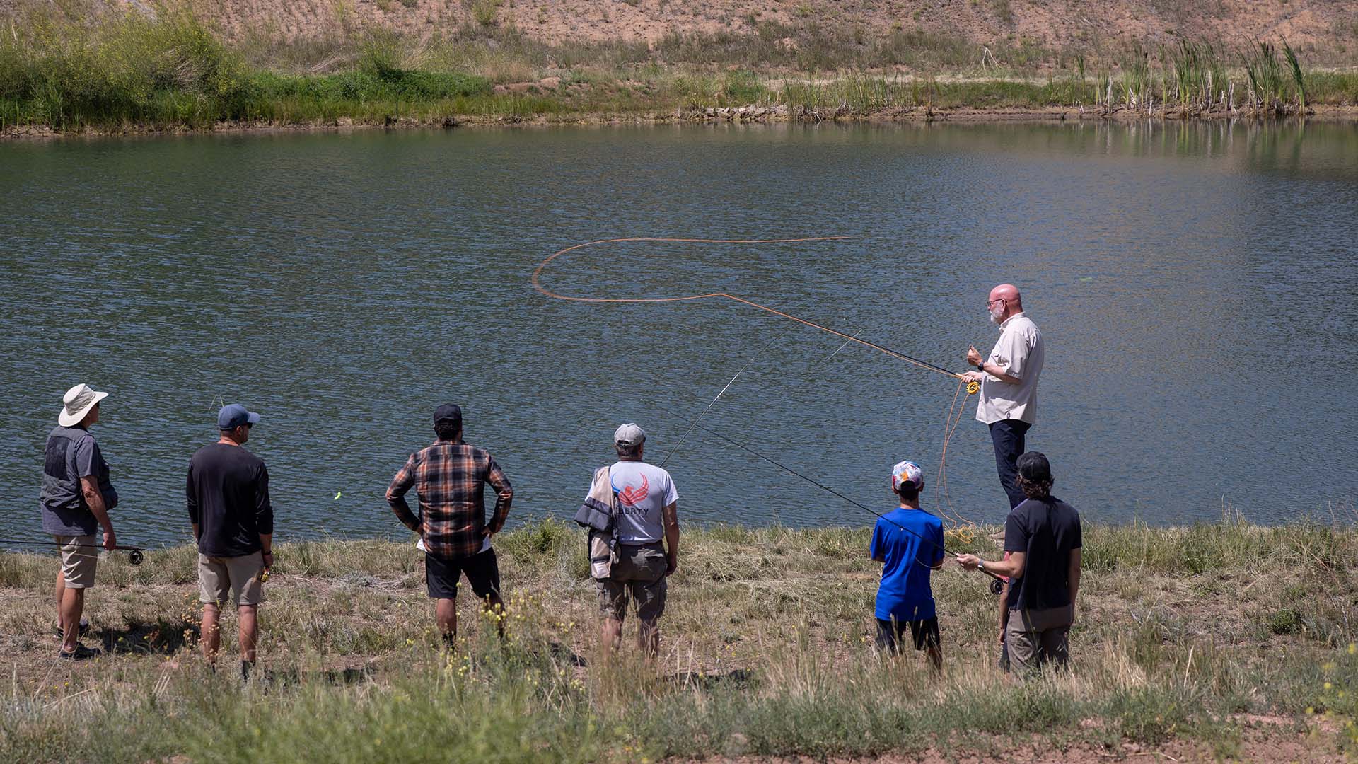 Instructor demonstrating a fly cast to a group of anglers during an on-the-water clinic at the TFO fly fishing school in Lake George, Colorado