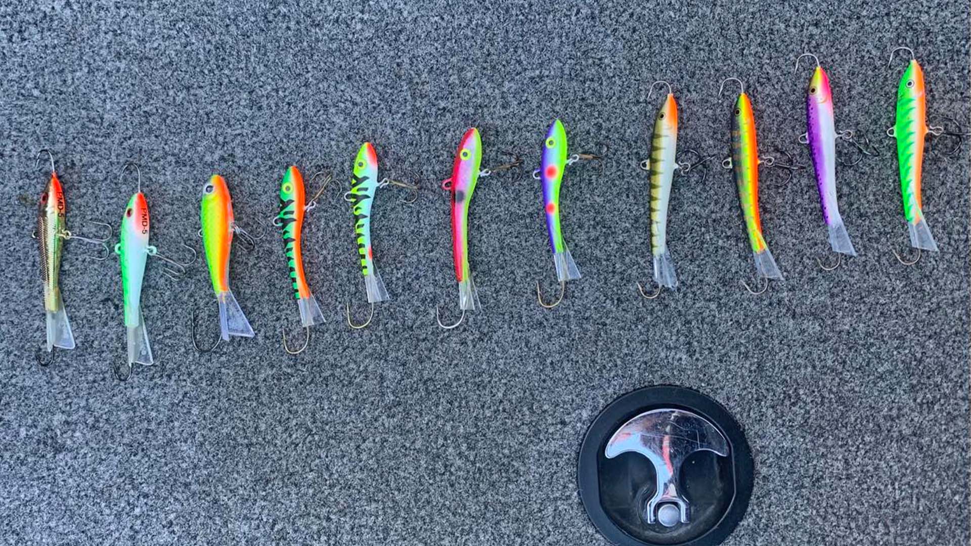 A lineup of colorful glide baits arranged on a boat deck, ready for targeting fall walleyes in deep water.