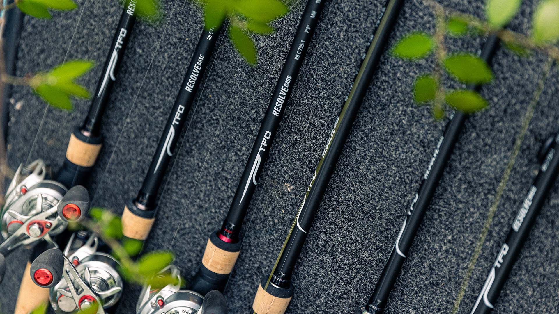 Close-up of TFO Resolve Bass rods lined up on a boat deck, ready for a day of fishing.
