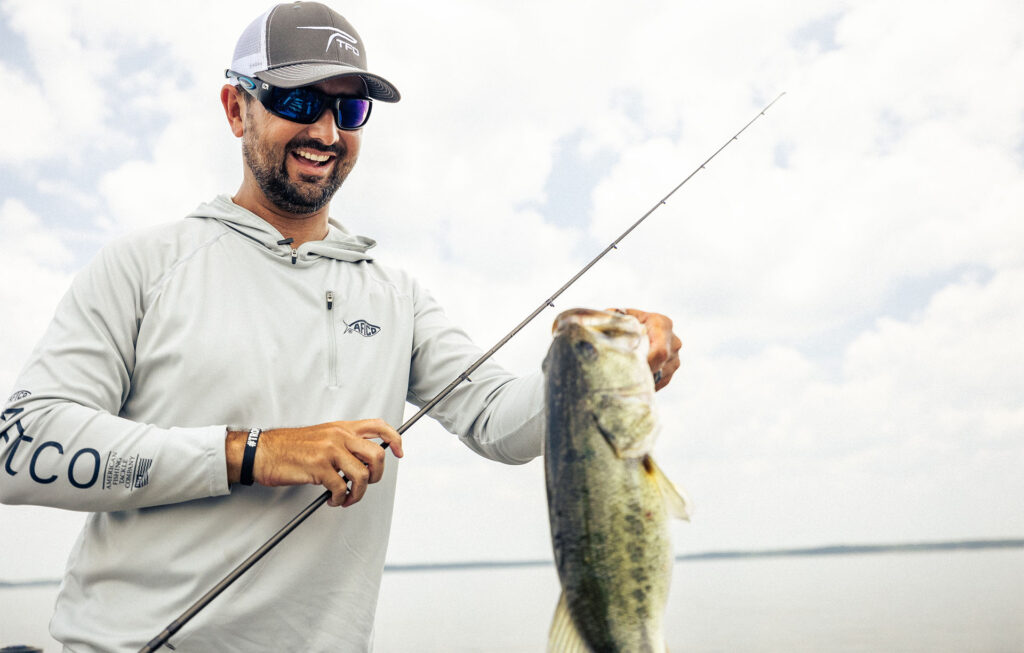 Nick LeBrun holding a largemouth bass caught on a TFO Taction Bass rod