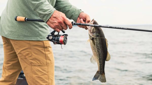 Angler holding largemouth bass caught on TFO Resolve RS6103F spinning rod